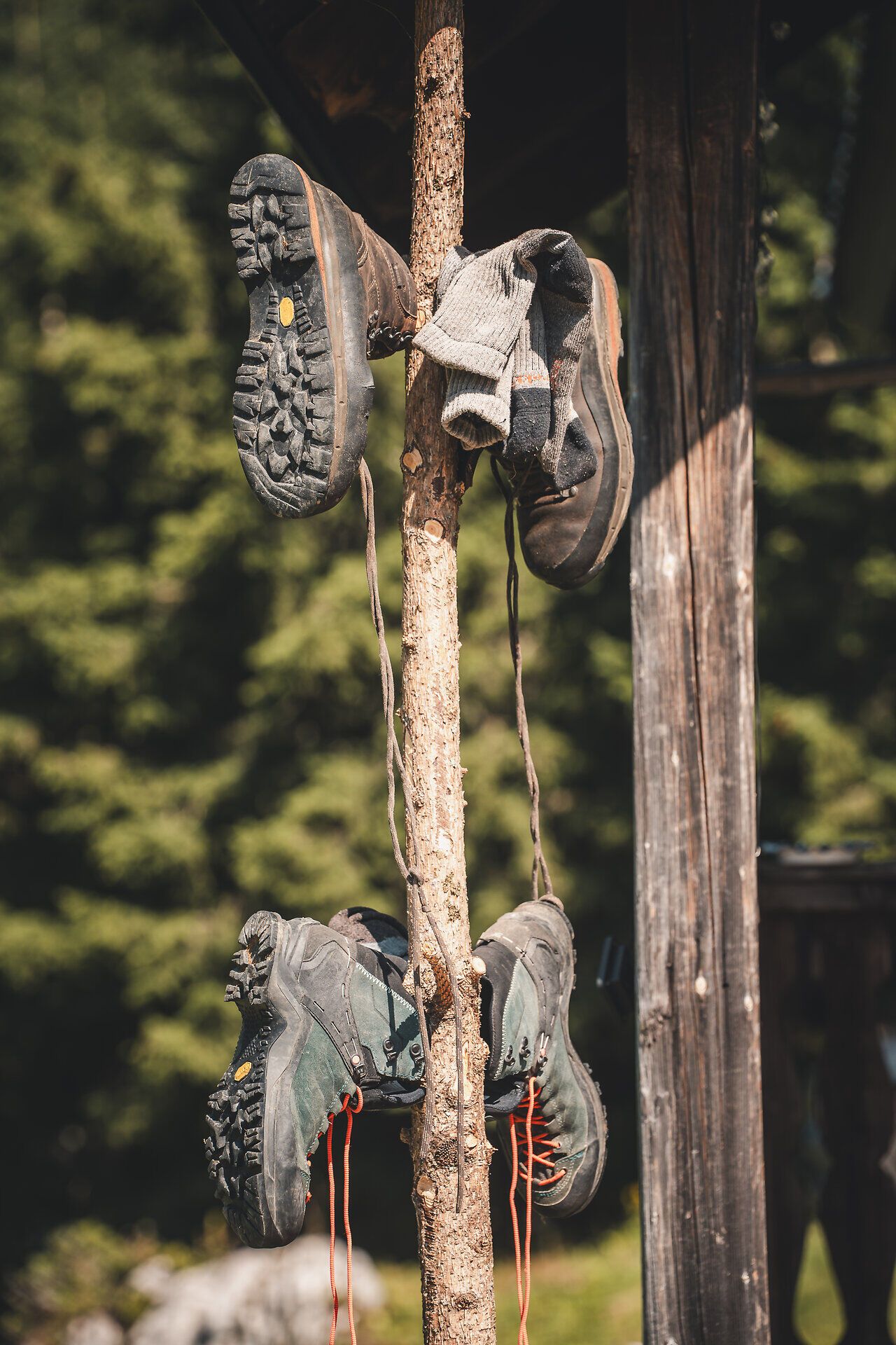 Unterschiedliche rustikale Gegenstände verziehren die Hochkaralm und machen die Atmosphäre besonders. Es wird Wert gelegt auf eine stimmungsvolle Einrichtung in jedem Detail. Auf dem Foto ist einen Holzstamm auf dem alte Wanderschuhe zum Auslüften hängen.