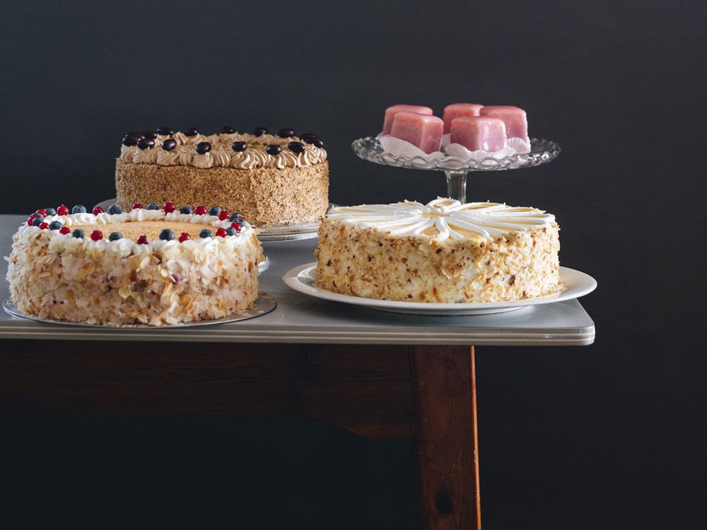 Drei Torten und rosa Gebäck auf einem Tisch.