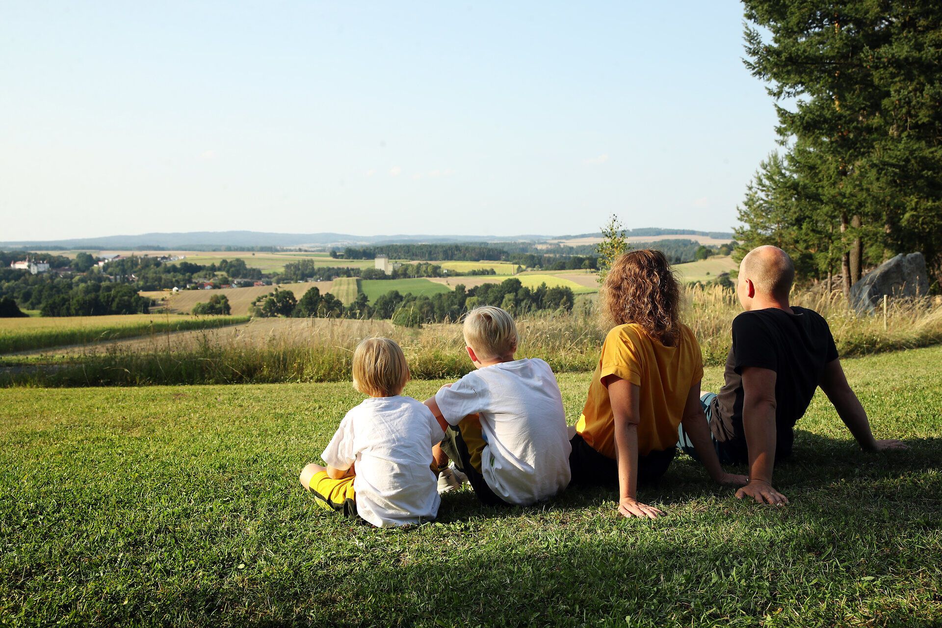 Eine Familie sitzt auf der Wiese und genießt die Aussicht im Naturpark Dobersberg. 