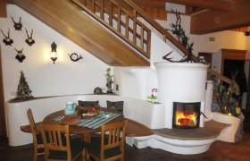 Gemütlicher Innenraum mit Kamin, Holztisch und Treppe.