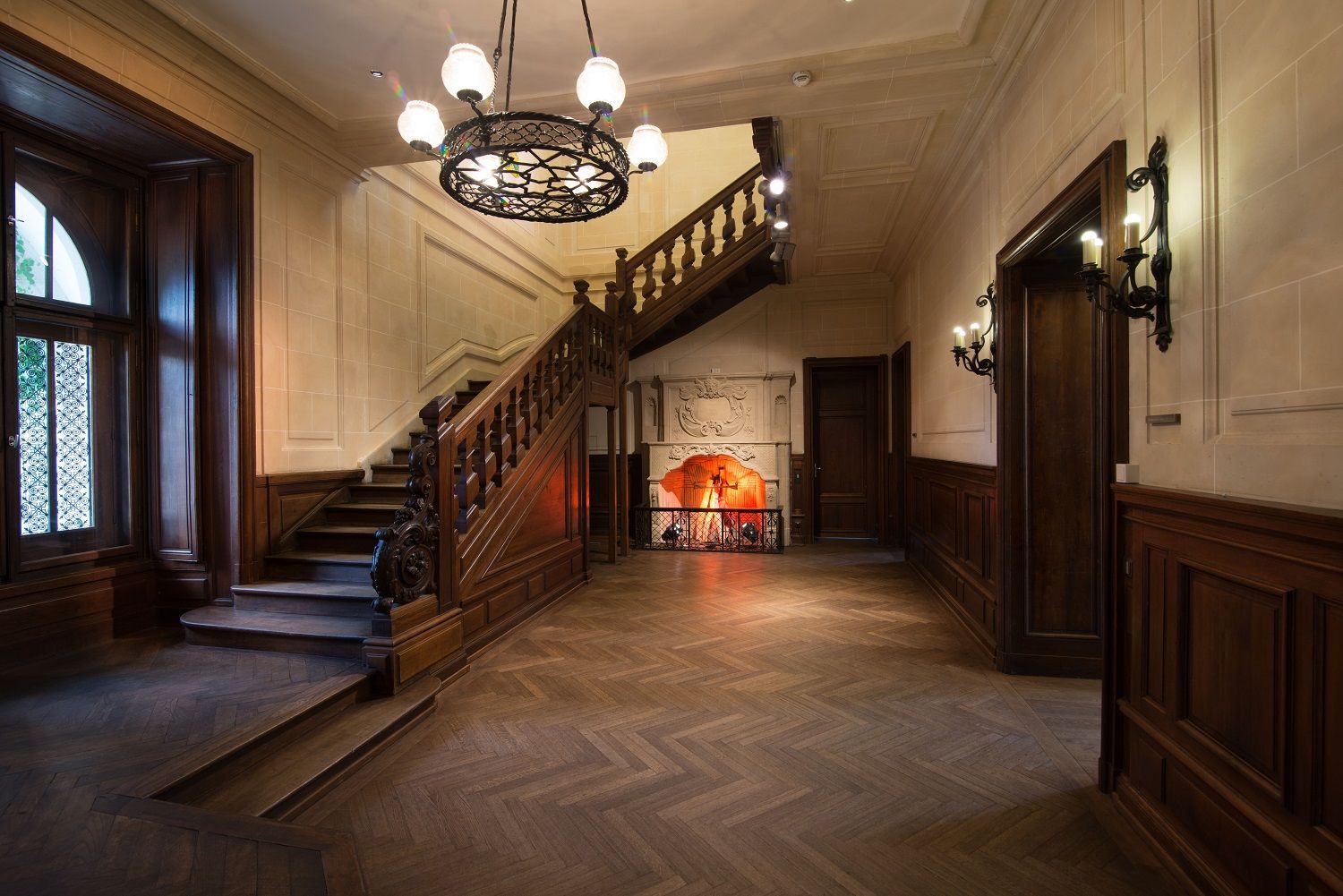 Eleganter Innenraum mit Holztreppe, Kamin und Kronleuchter im Schloss Rothschild.